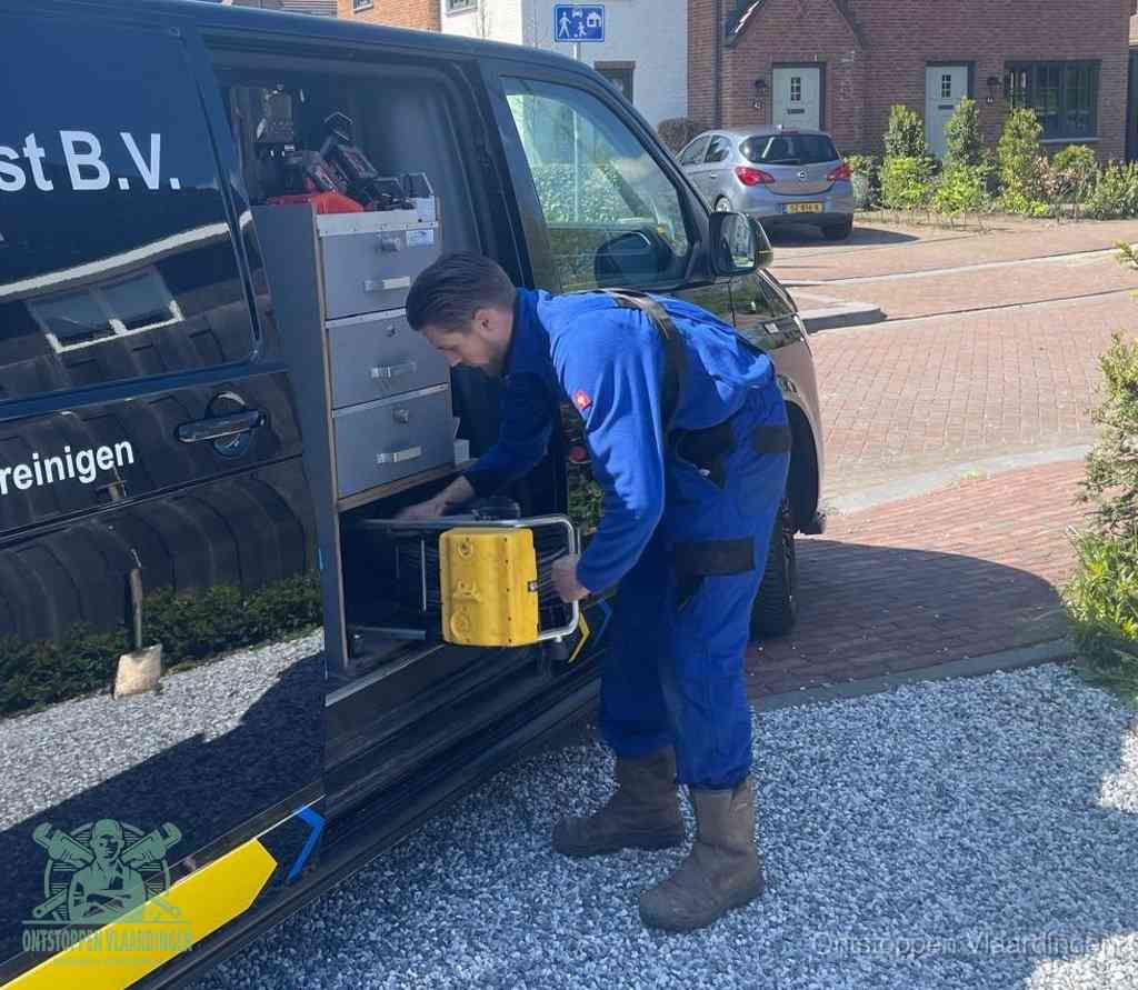 Een monteur pakt buiten op de oprit gereedschap uit de bedrijfsbus, het moment om een professional in te schakelen voor een verstopte afvoer in Vlaardingen