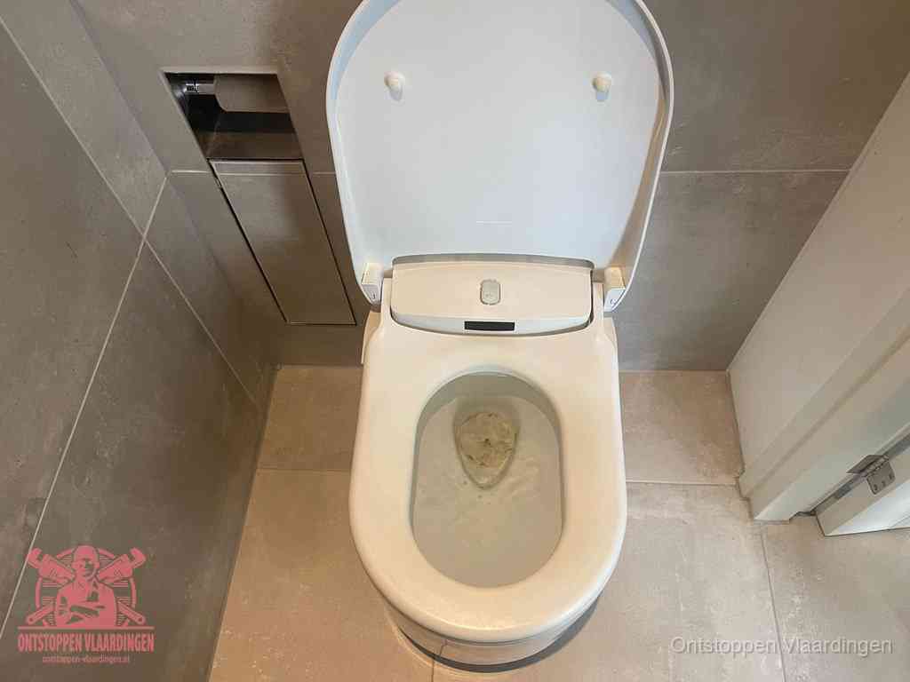 Een wit hangtoilet waarin een prop wc-papier op het water blijft drijven, een duidelijk signaal van een verstopte wc in Vlaardingen