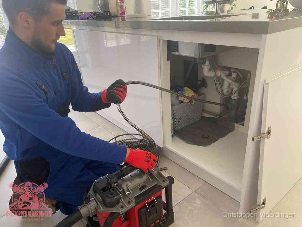 Een monteur reinigt de keukenafvoer grondig met een veermachine om terugkerende gootsteenverstoppingen te voorkomen in Vlaardingen