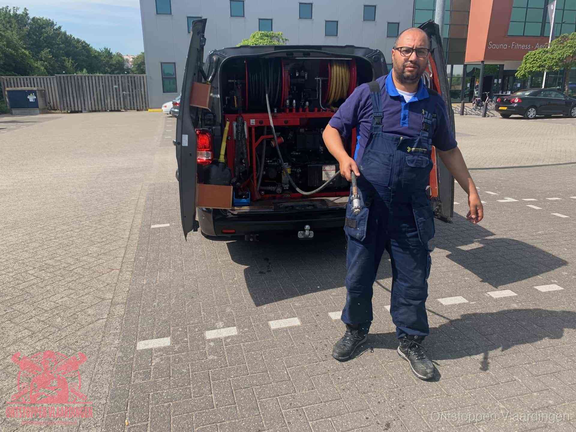 Een monteur bij zijn bestelbus met een hogedruk- en rioolreinigingsunit, klaar om de oorzaak van terugkerende wc-verstoppingen aan te pakken in Vlaardingen