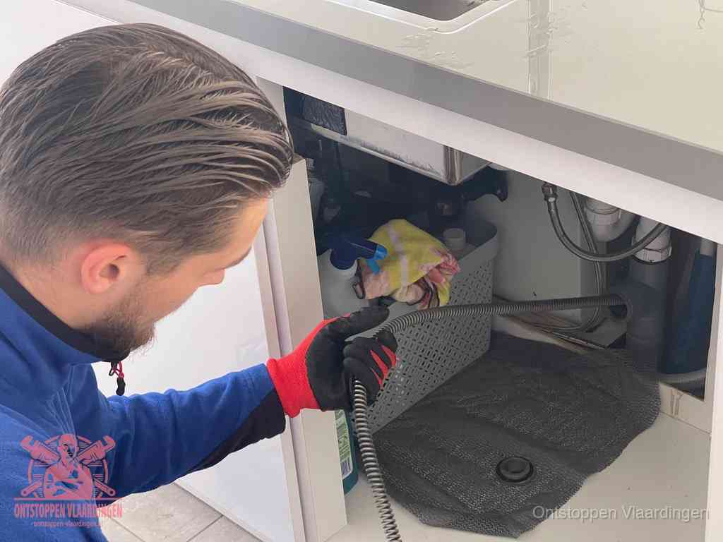 Een monteur voert een flexibele ontstoppingsveer in de afvoer om een verstopping voorbij de bocht van het toilet te bereiken in Vlaardingen