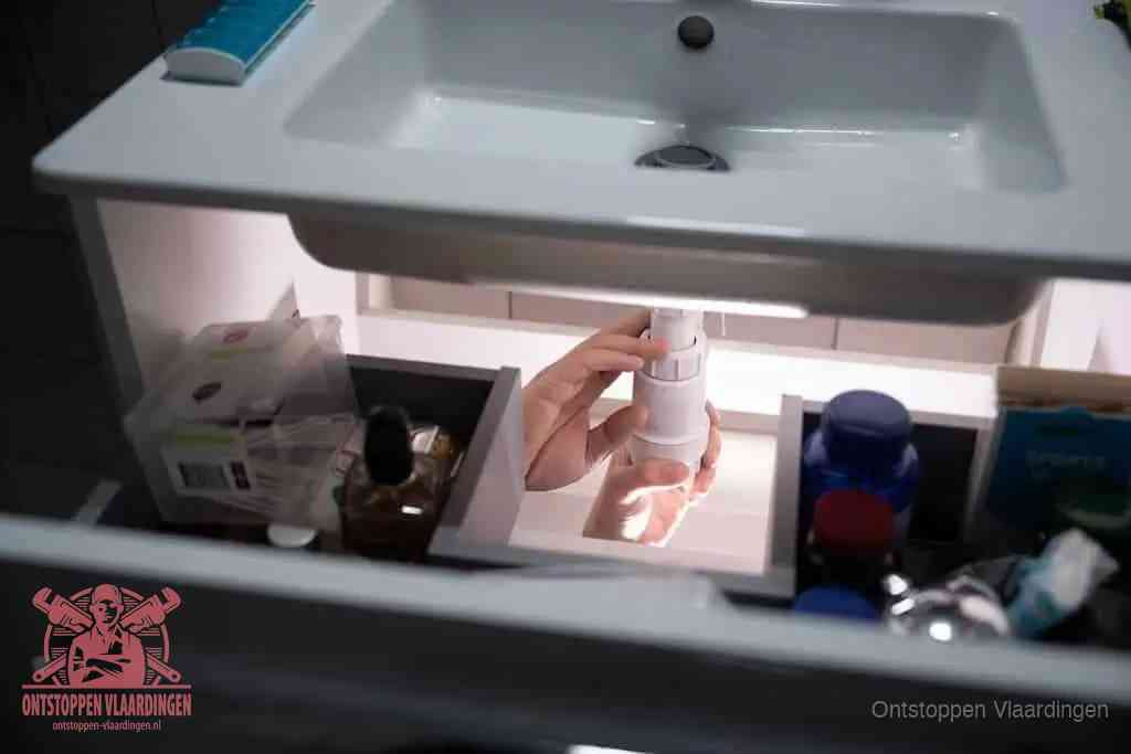 Een pompfles met zeep boven een wastafel in de toiletruimte, de warm water en afwasmiddel-methode om de wc te ontstoppen in Vlaardingen