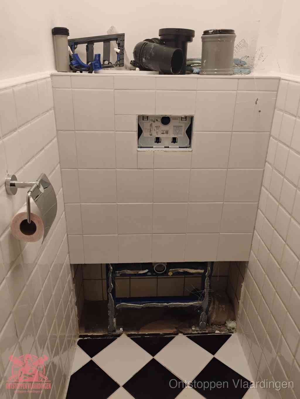 Een toiletruimte waar het hangtoilet en de inbouwreservoir-onderdelen zijn vrijgelegd voor onderhoud, periodiek nazicht voorkomt een wc-verstopping in Vlaardingen