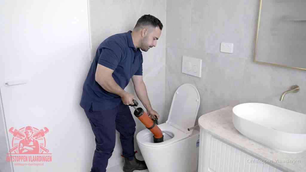 Een monteur gebruikt een handmatige perspomp (toiletontstopper) op een wandcloset tijdens het professioneel wc ontstoppen in Vlaardingen
